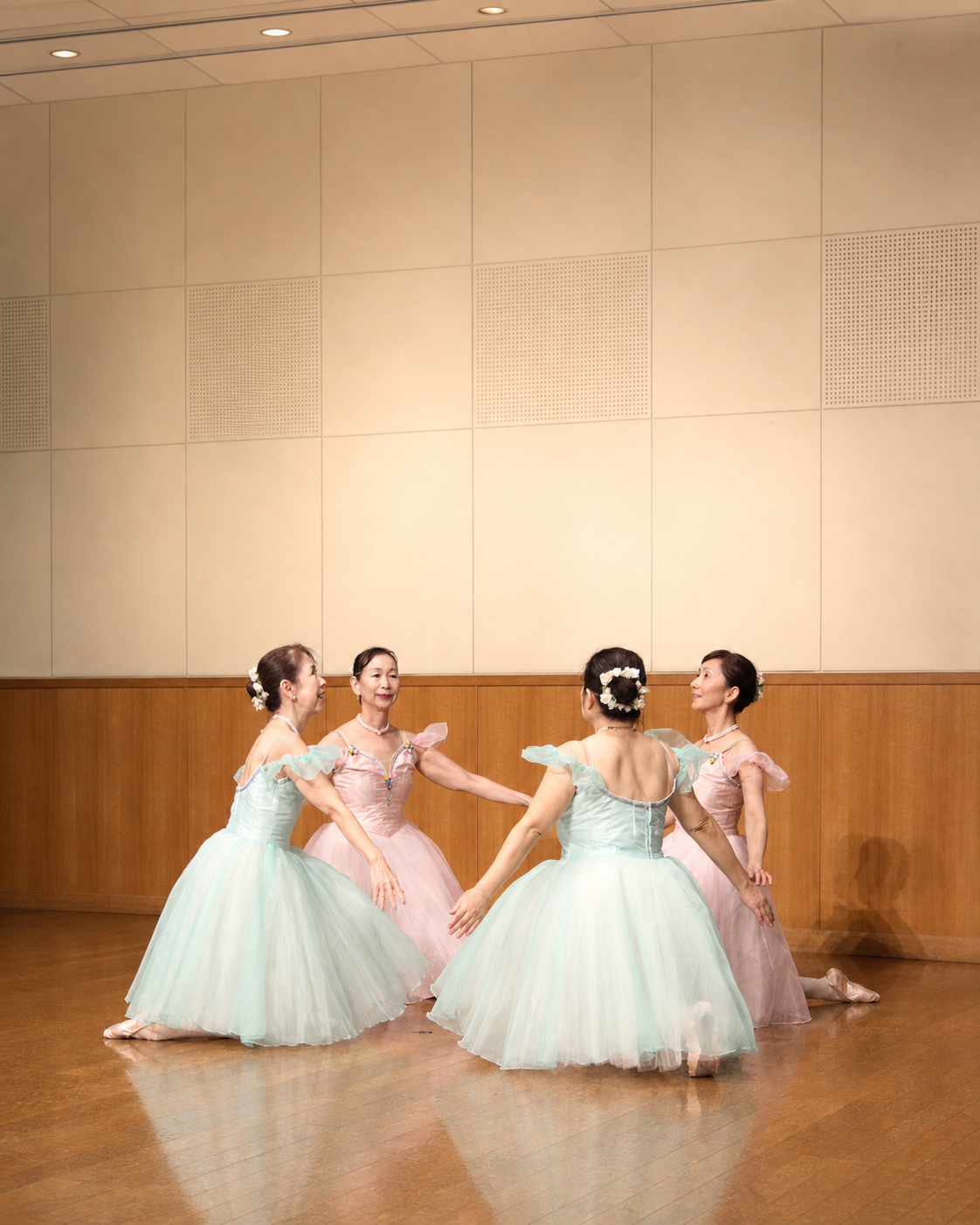 淡い色の衣装で輪になって踊る大人のバレエダンサー
